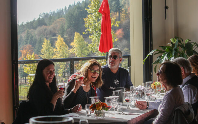 A group of people smiling and enjoying wine tasting at St. Innocent Winery