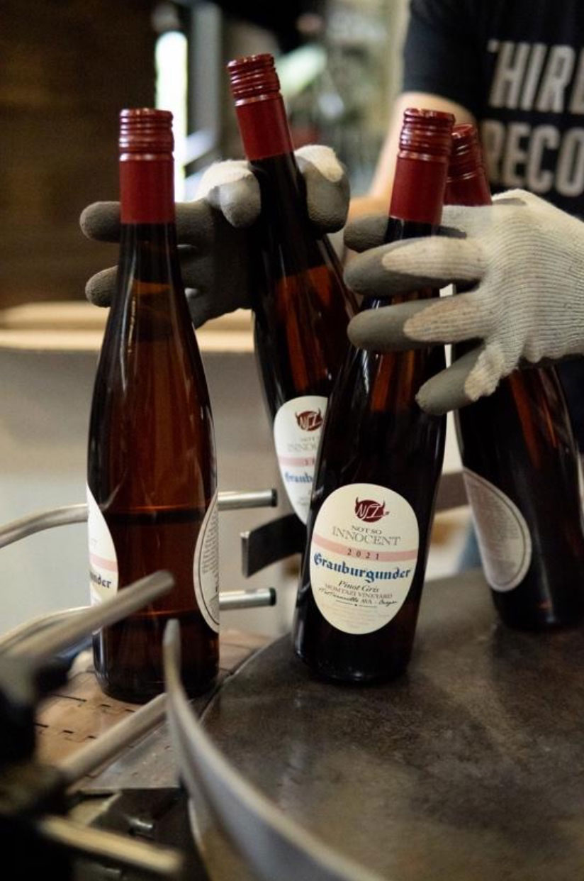 Hands transporting freshly bottled wines during production