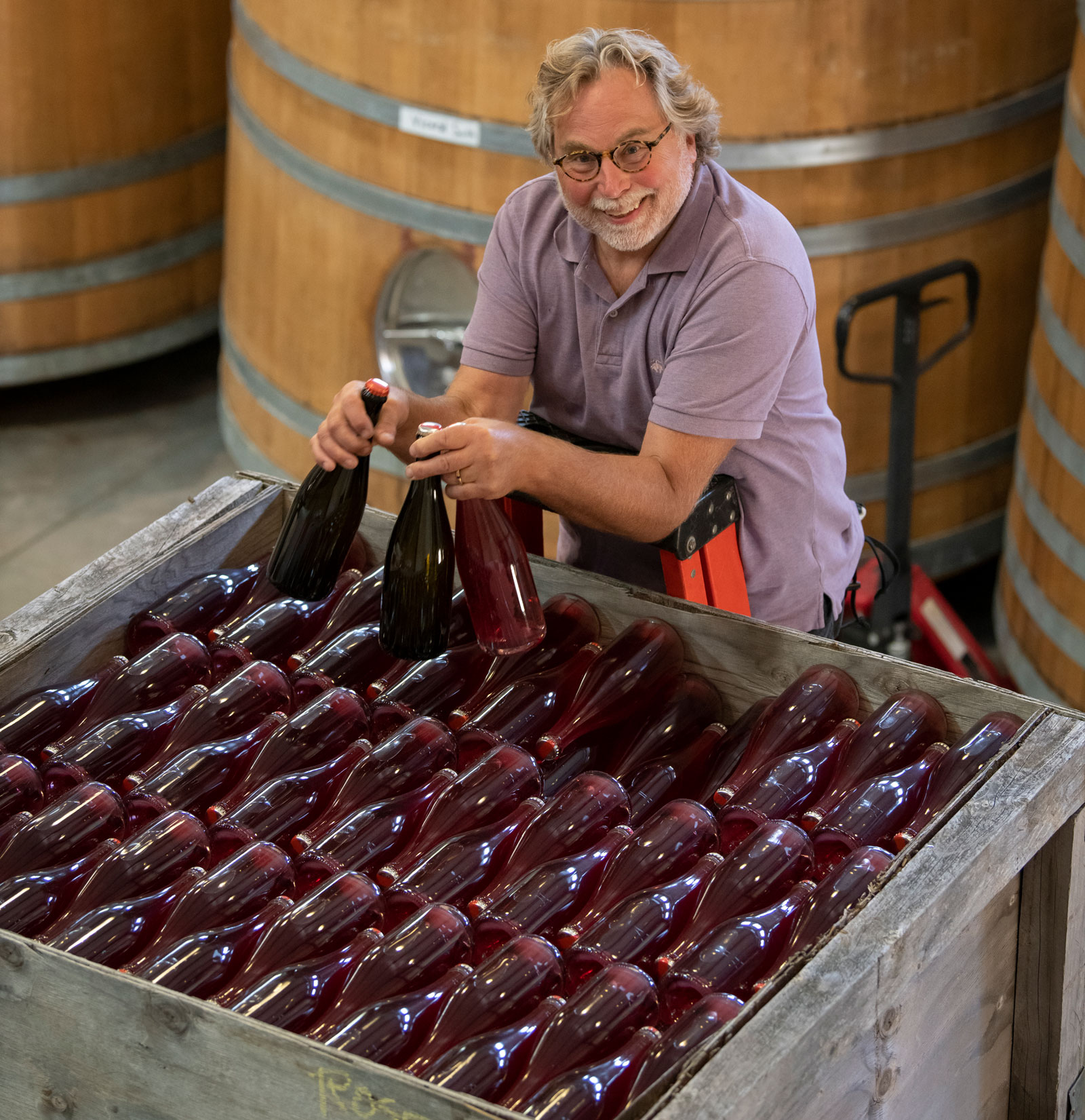Mark Vlossak standing over a large container of sparkling wine bottles